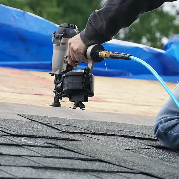 Close up of a roofer installing new shingles with a nail gun